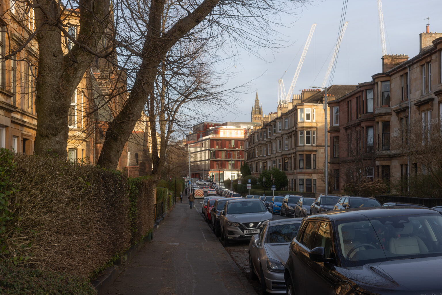 Lawrence Street, Dowanhill, Glasgow blonde sandstone tenements with cars and modern Glasgow University building and church spire in background