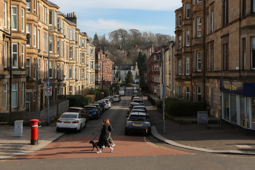 Walton Street in Shawlands, Glasgow, sandstone tenements with a red postbox and a dog walker