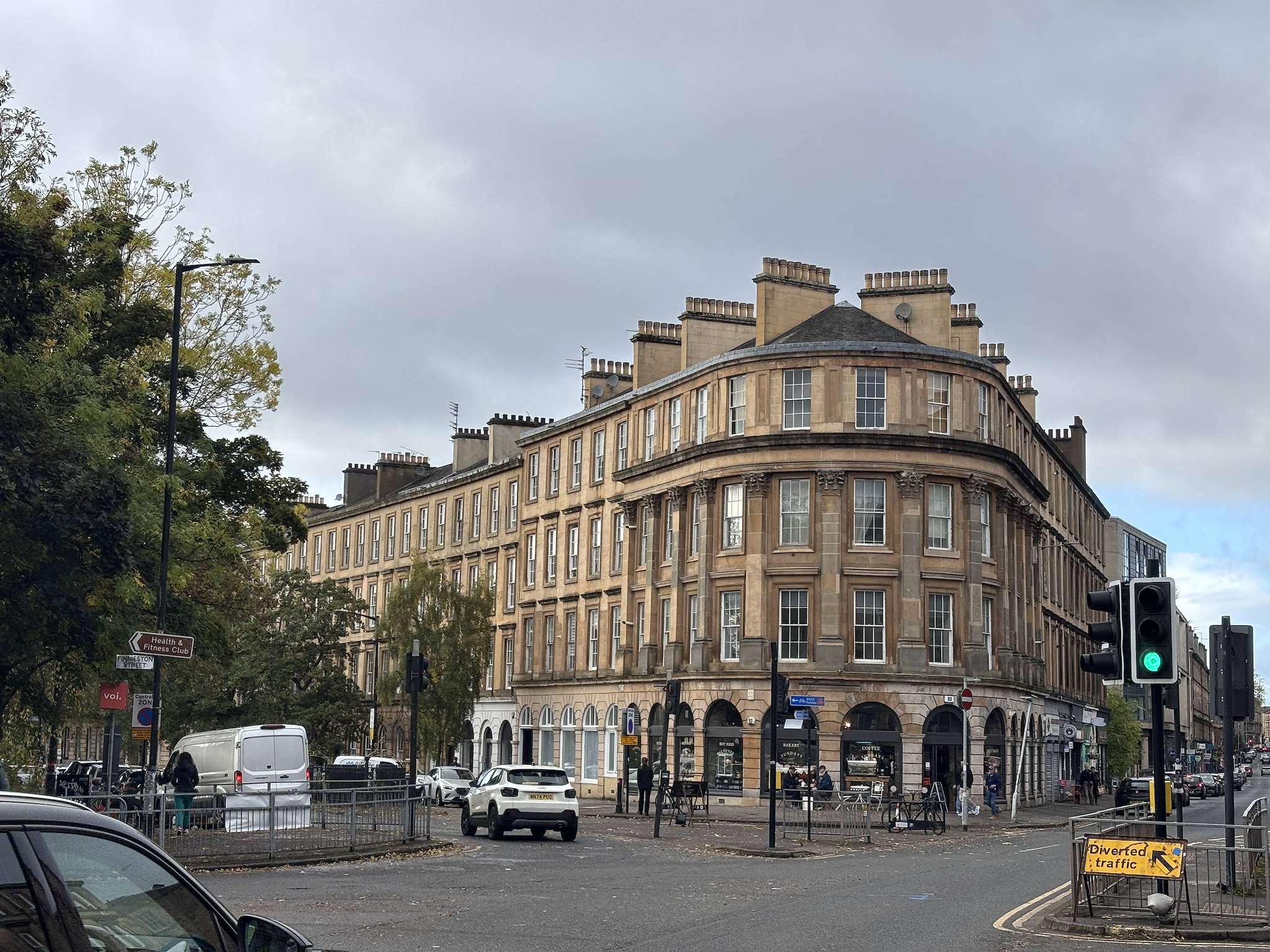 Finnieston Street, Finnieston, Glasgow, a curved blonde sandstone corner building with shops at street level and traffic lights at the junction