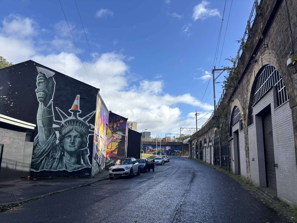 Eastvale Place, Finnieston, Glasgow, a Statue of Liberty mural on a gable end opposite the railway arches, with parked cars along the street