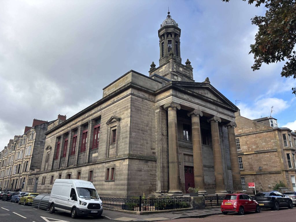 Bentinck Street, Finnieston, Glasgow, a columned stone church with a tall tower beside sandstone tenements and a parked white van