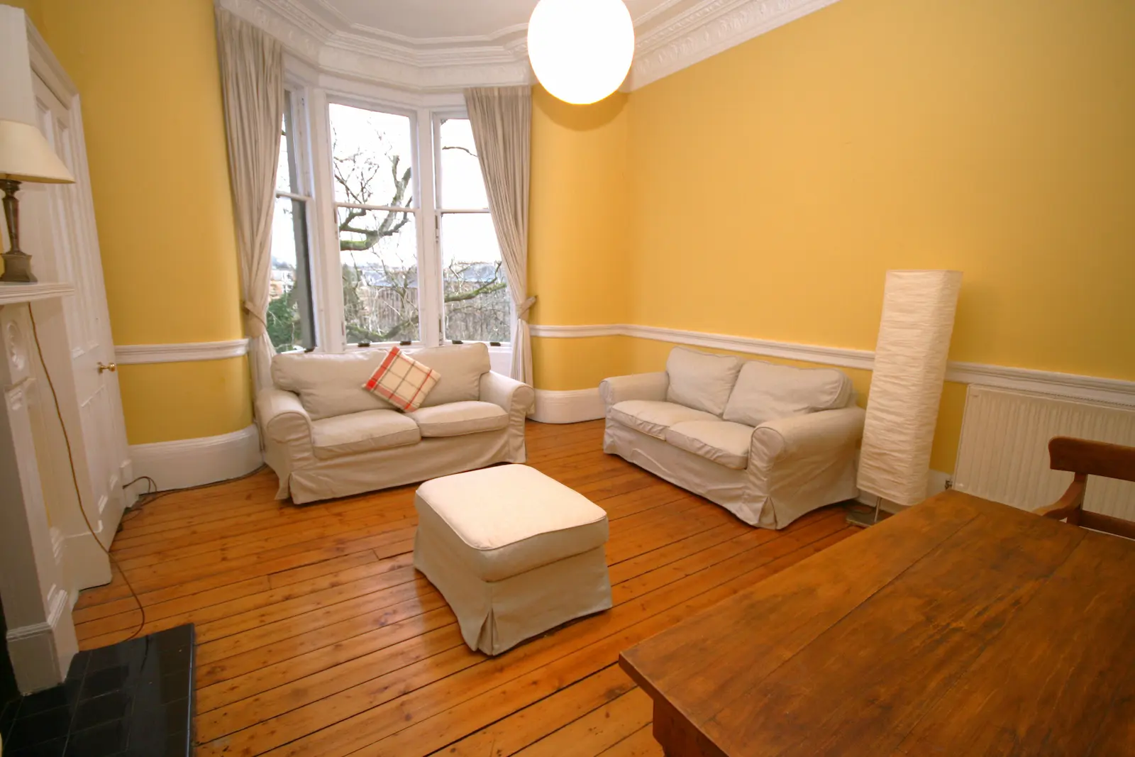Tenement flat living room with a bay window, two sofas and a timber floor, Glasgow