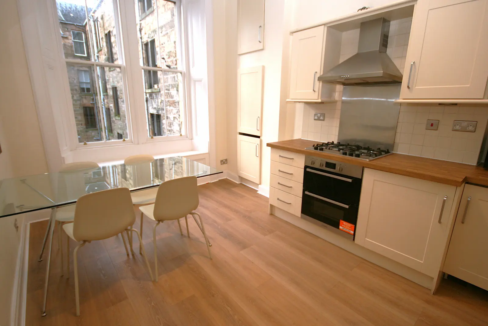 Tenement flat kitchen with a tall sash window and a glass dining table, Glasgow