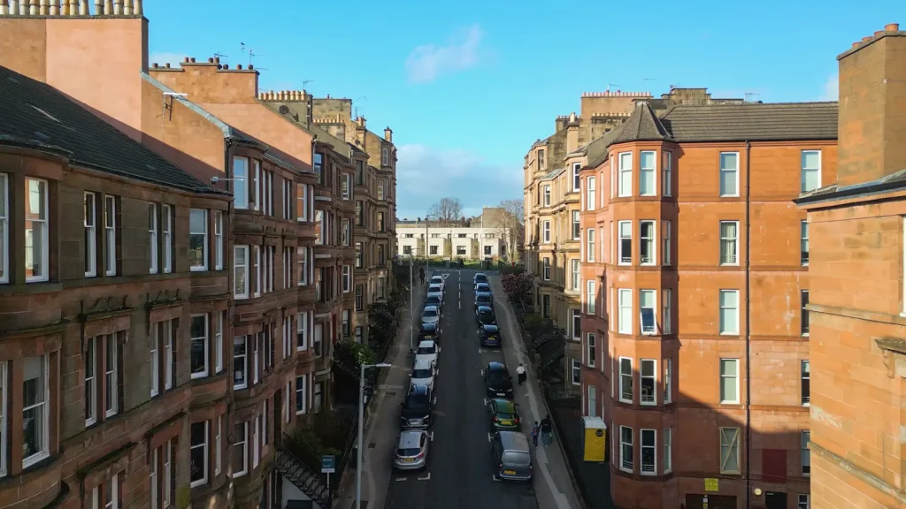 Aerial view along a street of red and blond sandstone tenements in Glasgow's West End